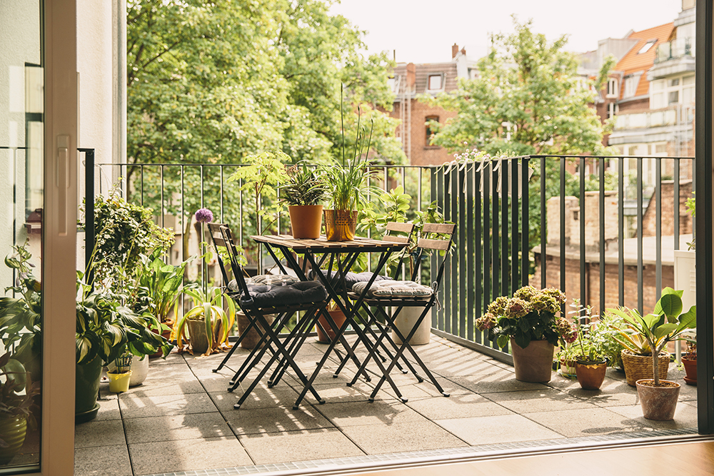 A fenced-in patio with simple outdoor dining set surrounded by potted plants.