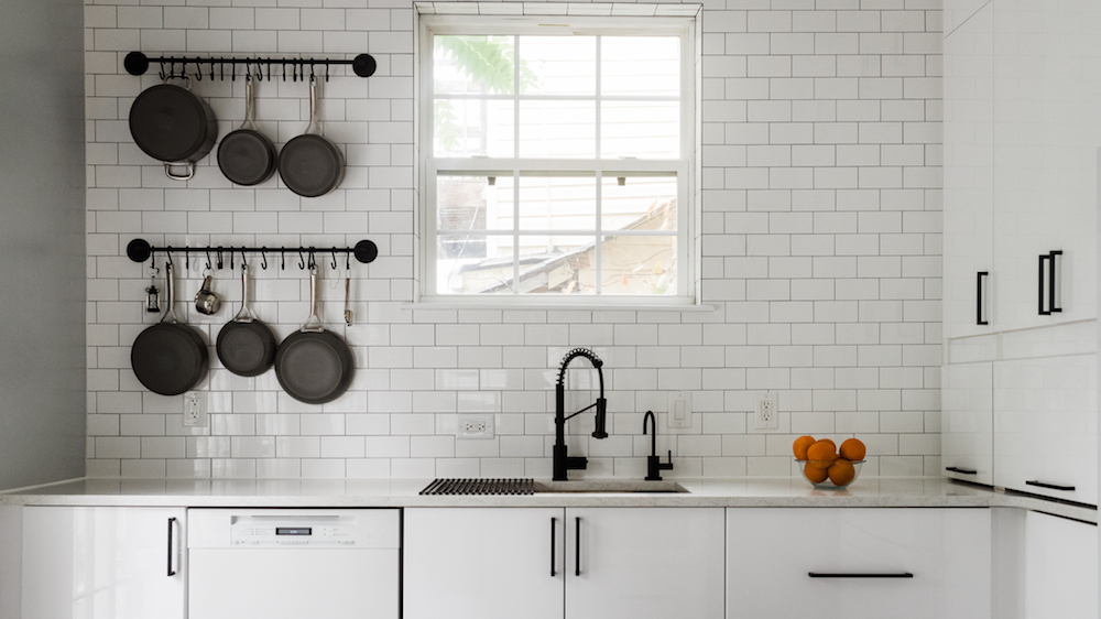 sparse white kitchen with hanging black pans