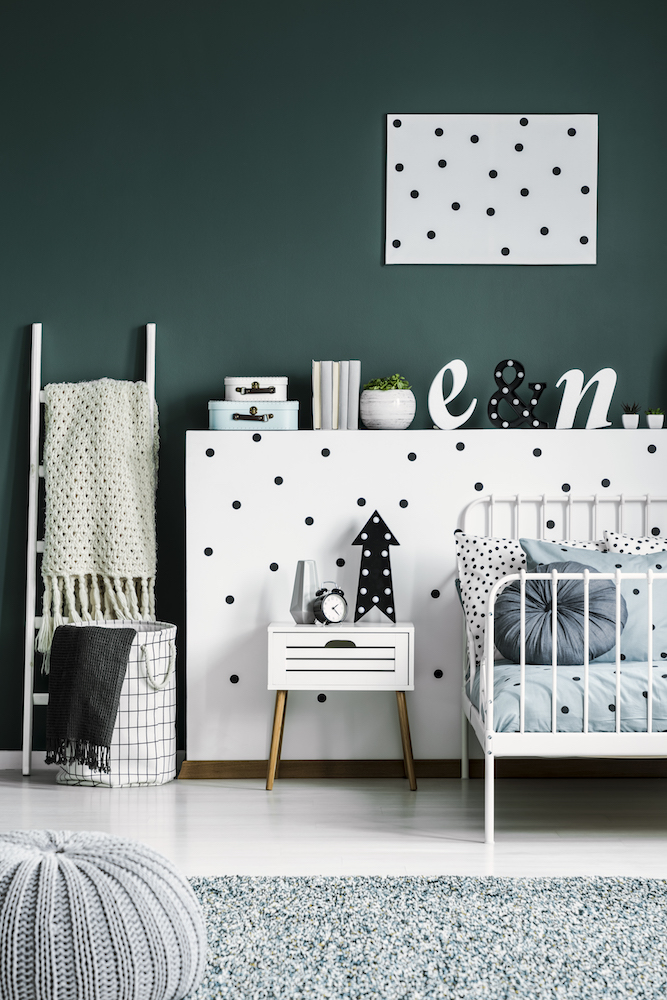 Polka dot poster on a dark green wall in a scandinavian style white bedroom interior