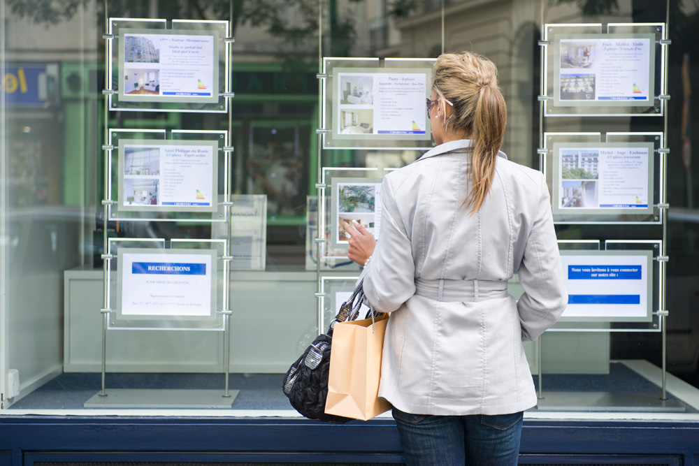 Woman looking at listings on window