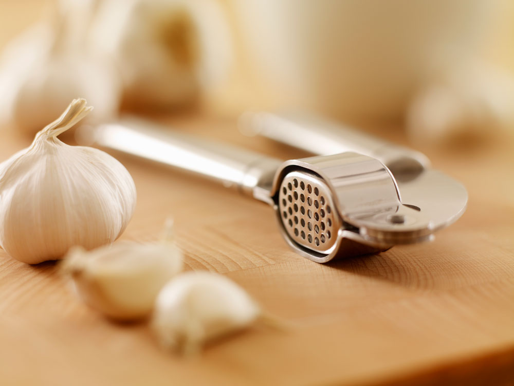 Cloves of garlic spread out around a mincer