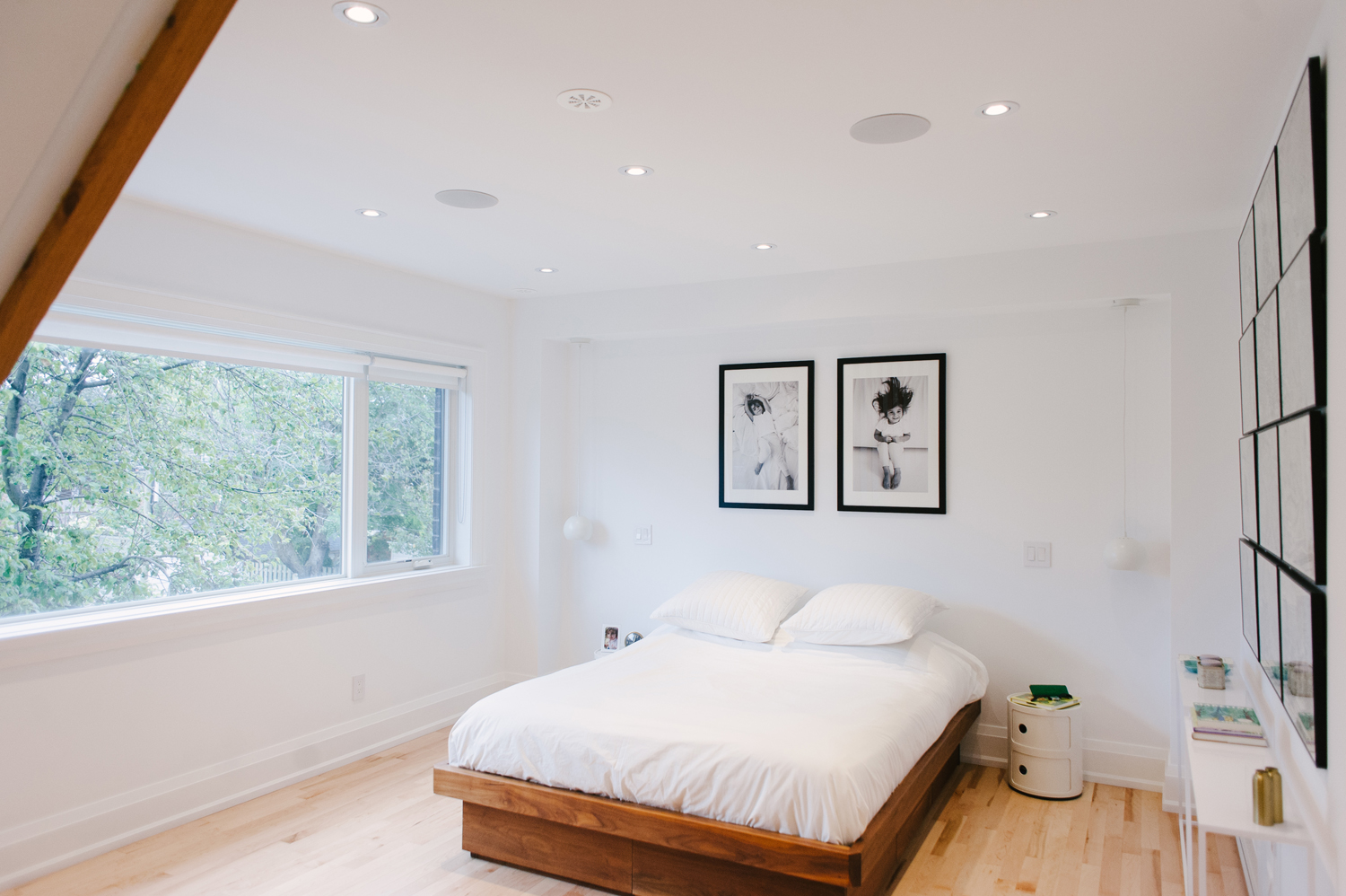 Low wooden bed frame in all-white master bedroom