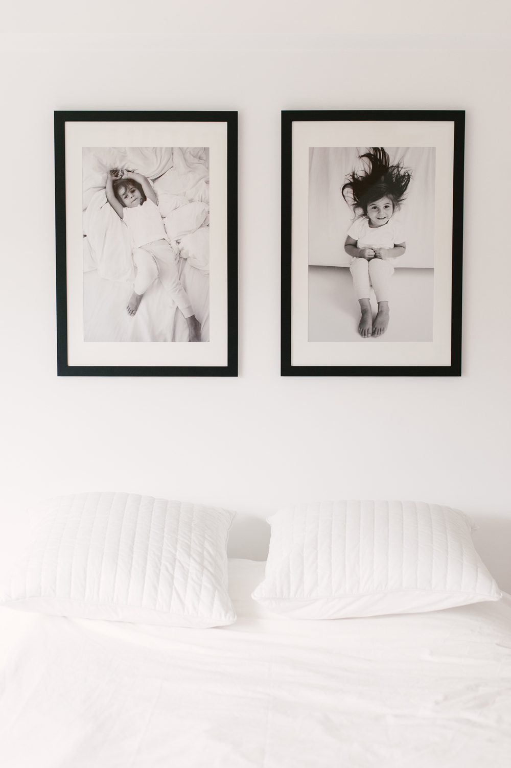 Black and white prints of child hanging over white bed