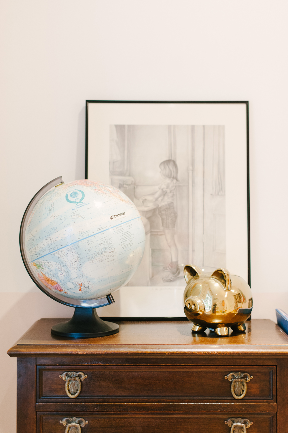 Vintage globe and gold piggy bank on antique dresser