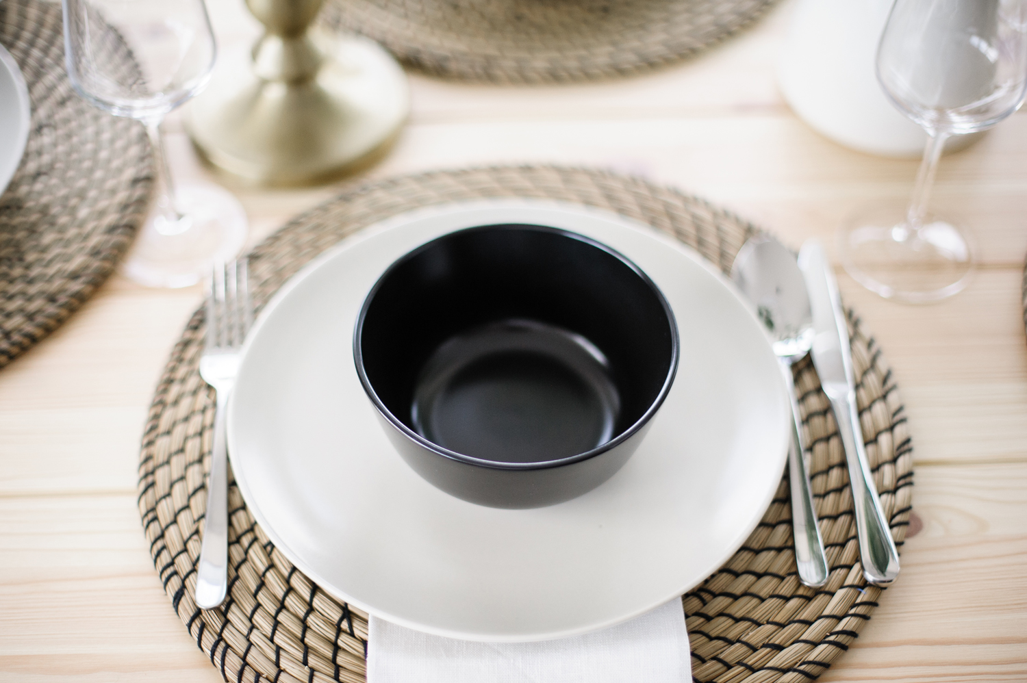 Table setting with woven charger and black bowl