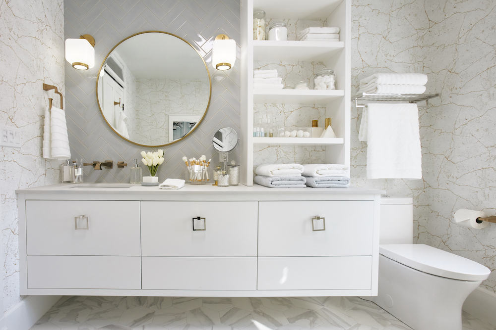 A white floating vanity in a renovated bathroom with stacked shelves for more storage