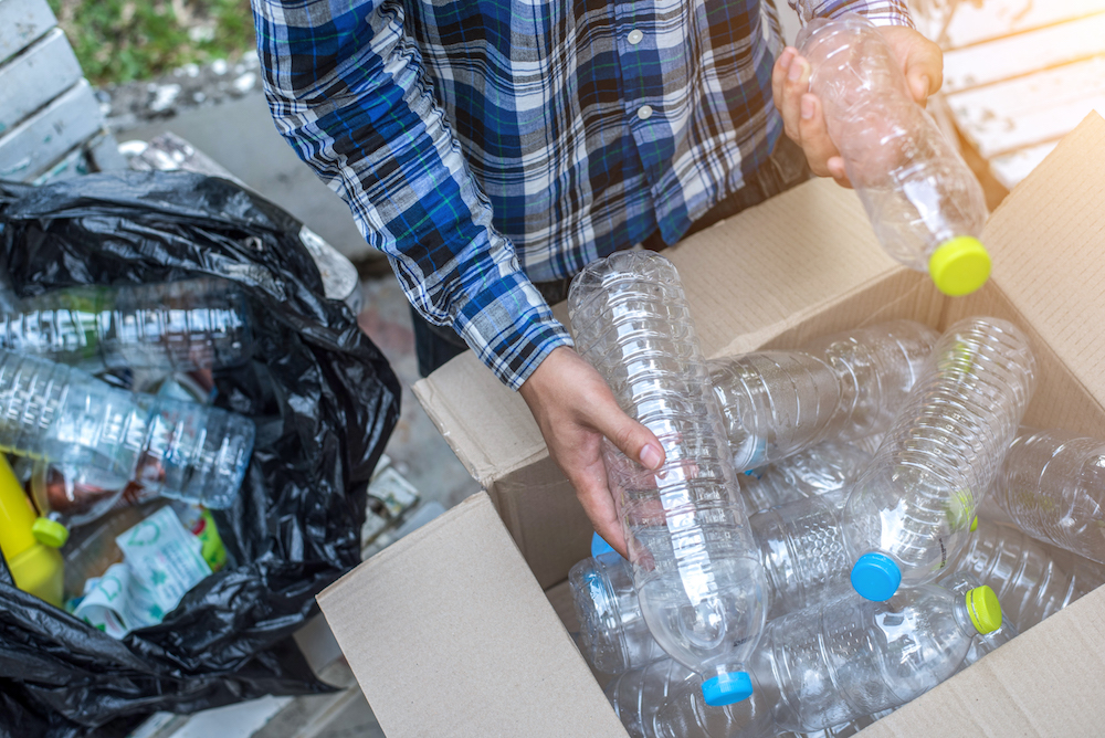 Hand holding recyclable plastic bottle in garbage bin