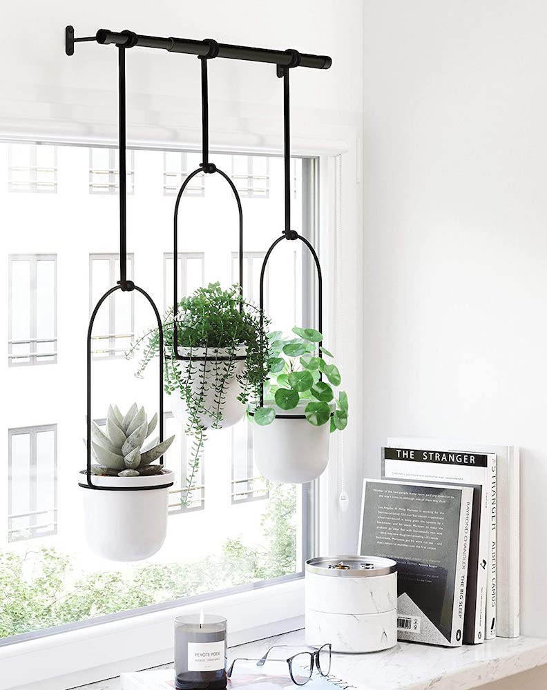 white hanging planters in front of window in white room