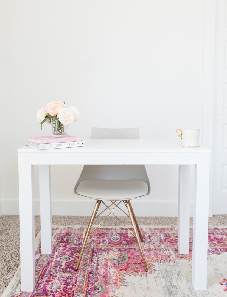 white desk and chair on top of patterned pink area rug