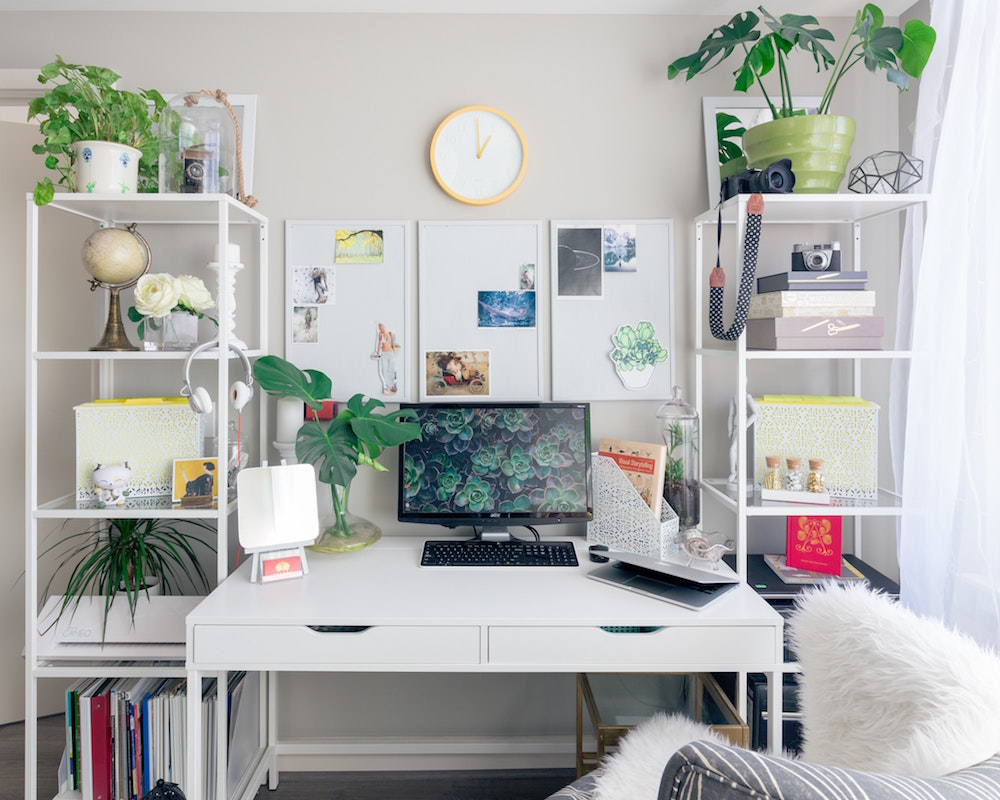 white home office desk framed by tall white shelves