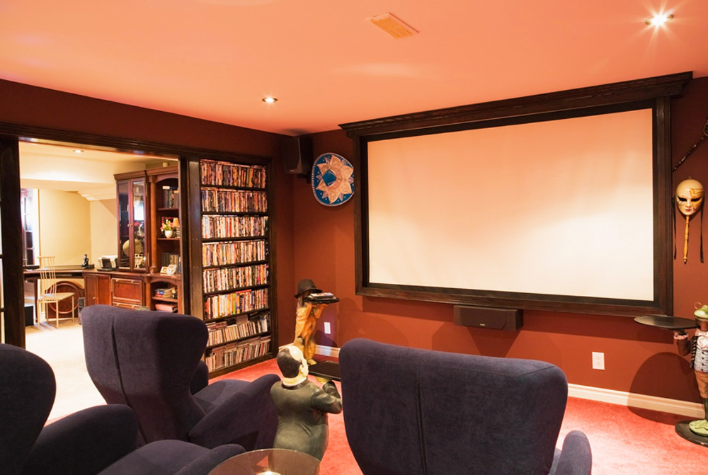 A basement home theatre with cushy chairs and an oversized screen