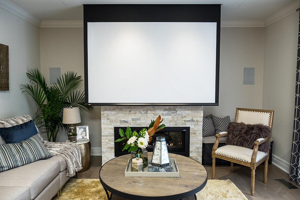 A home theatre with a pull-down screen above a gas fireplace