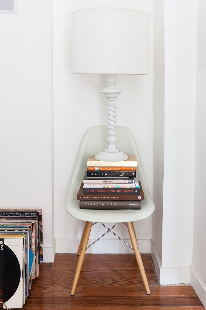 stack of books on chair in corner of white living room