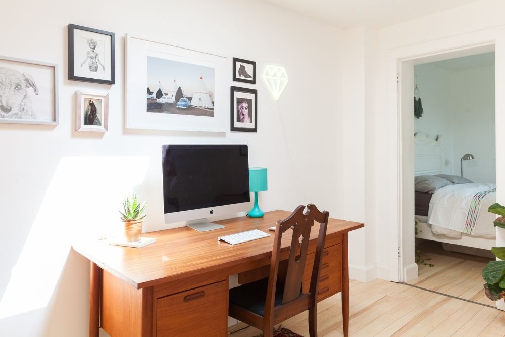 white home office with gallery wall and wooden desk