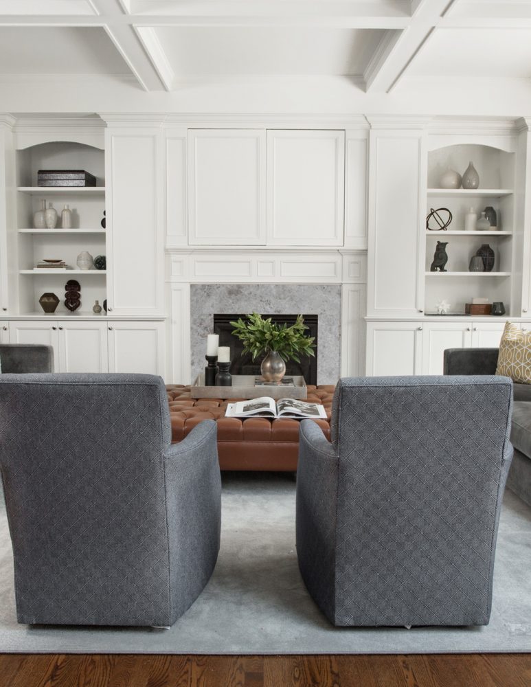 back of two grey chairs facing living room fireplace