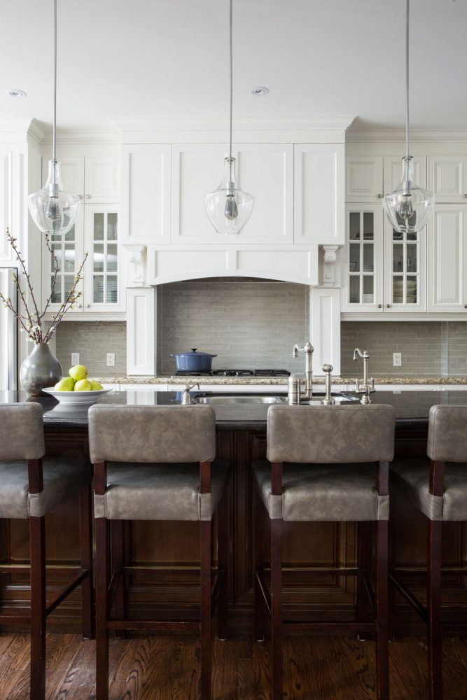 three clear pendant lights, kitchen island with grey stools