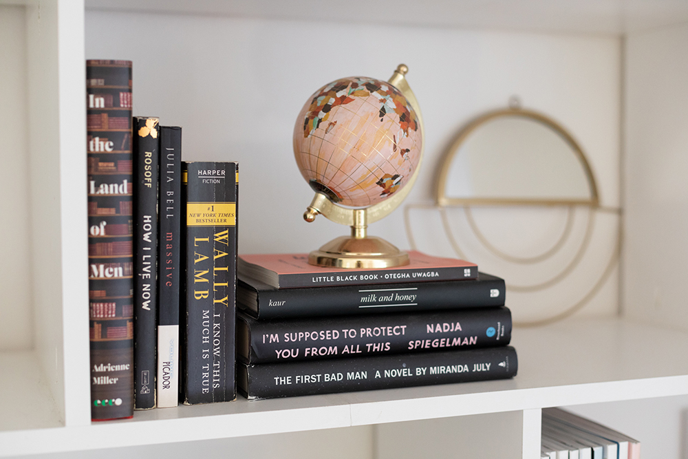 Bookshelf with stack of books and small pink globe