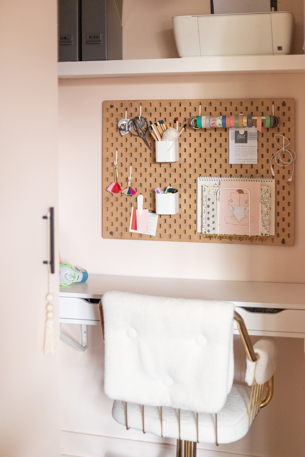 White desk, gold chair and pegboard on wall