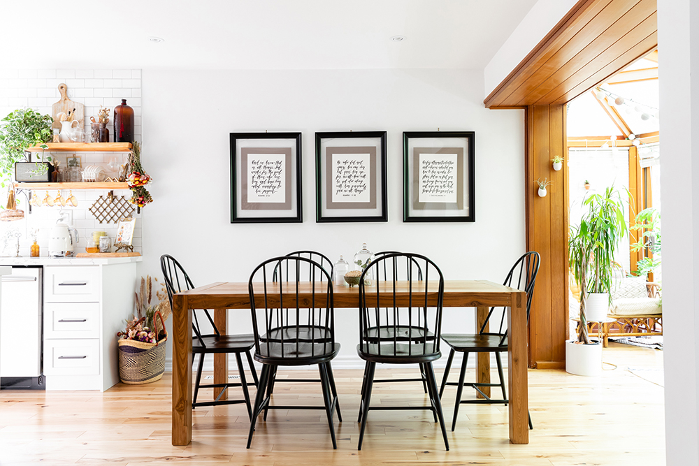 Dining room with three pieces of artwork hanging above the wooden dining room table