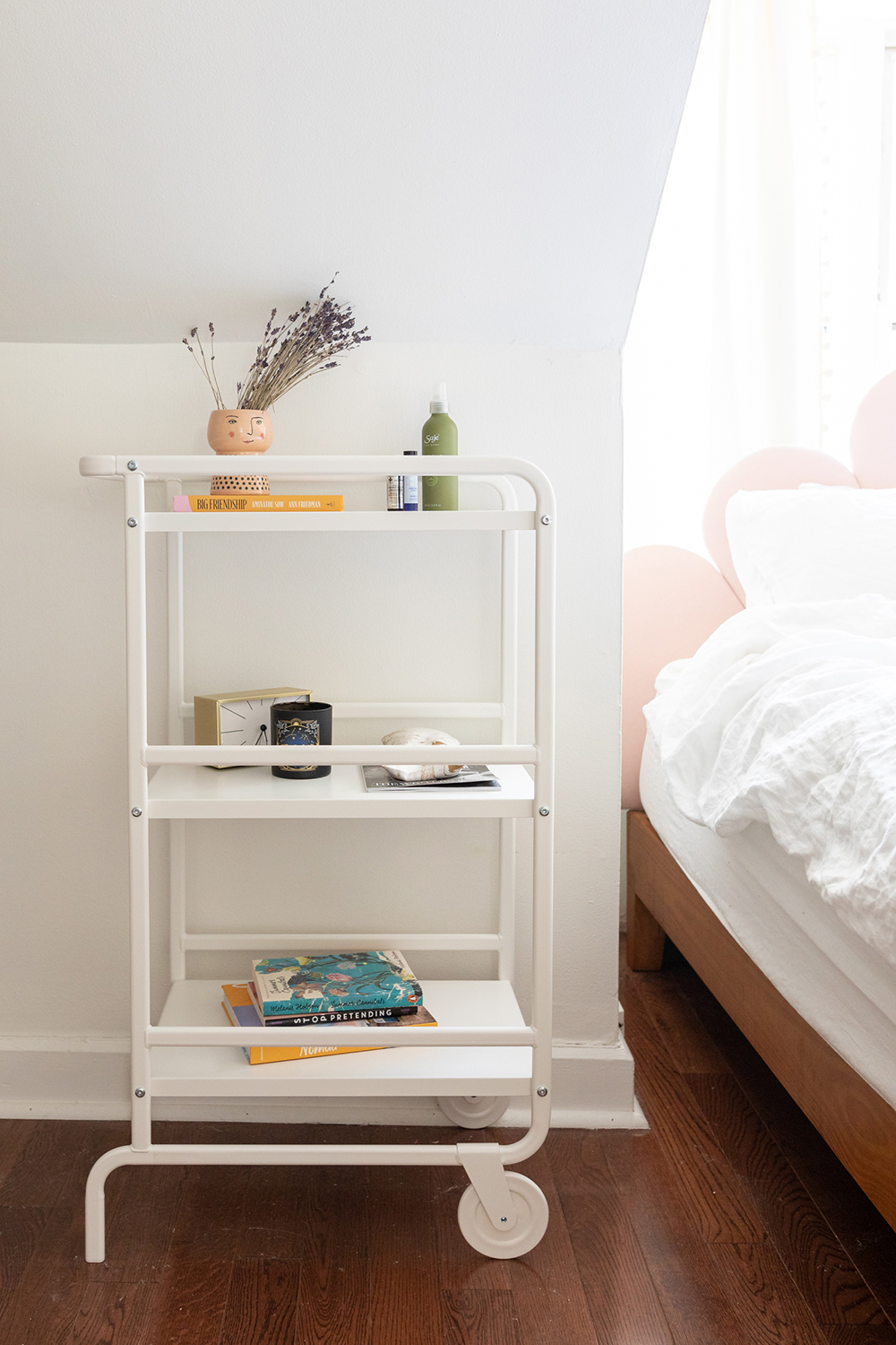Bedroom nightstand with books, clock and lavender sitting on top