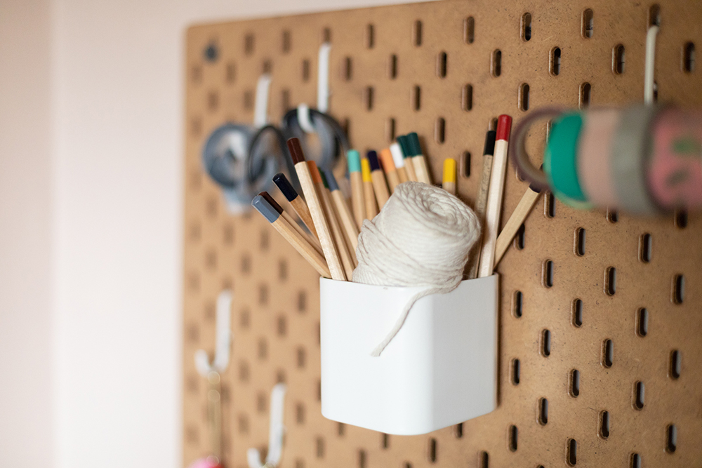 Closeup of pegboard on wall with art supplies attached