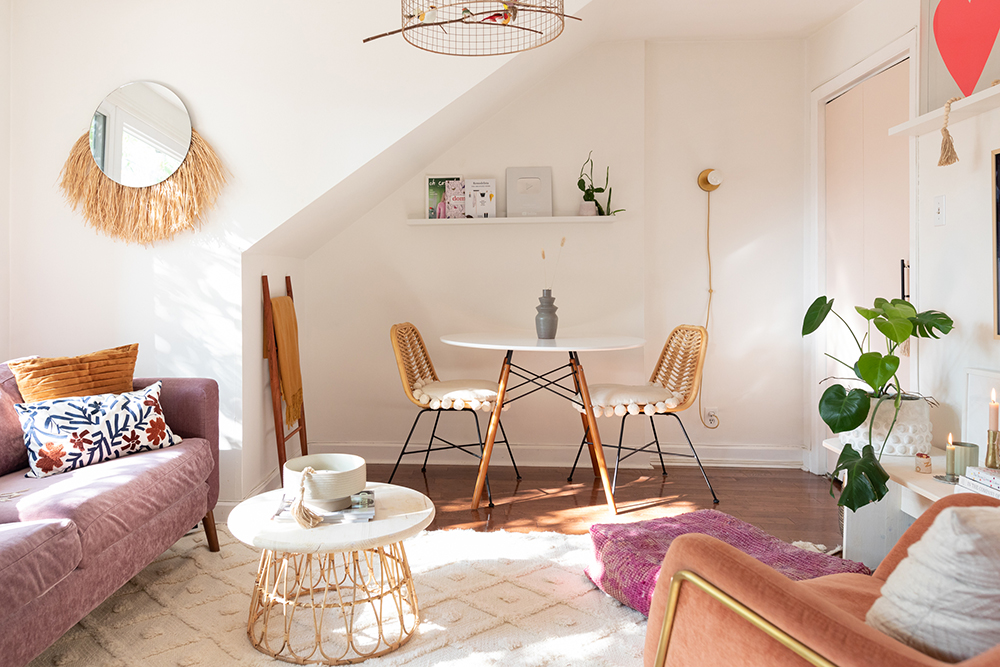 Boho living room with pink couch, orange chair and dining room table