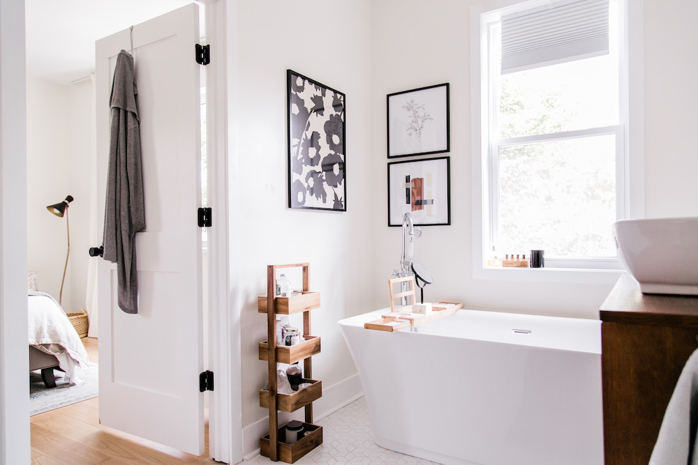 white bathroom with freestanding tub and wall art