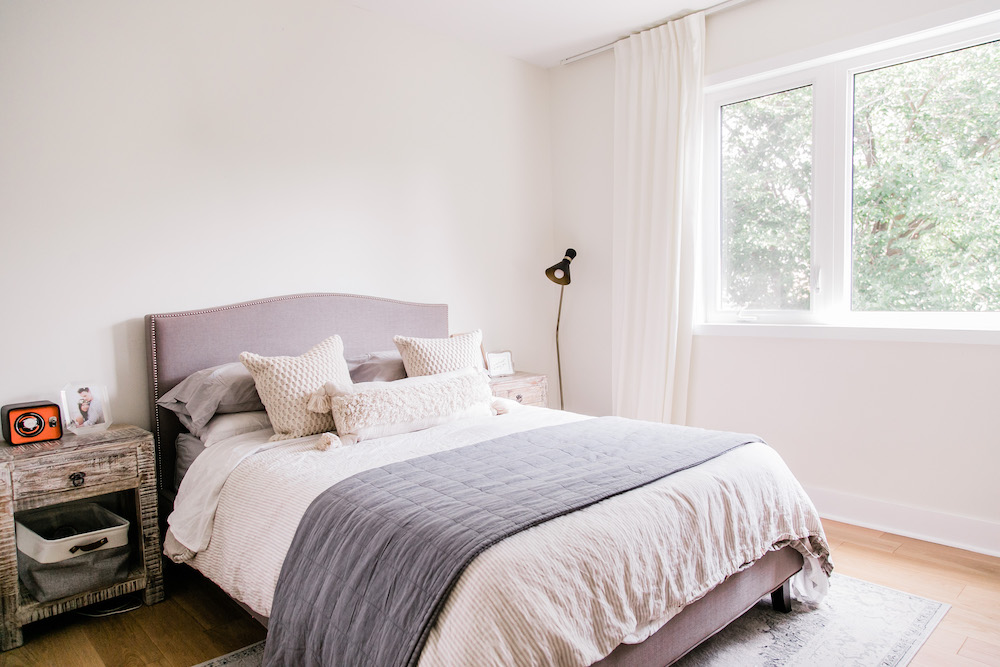 white bedroom with grey bed and wood nightstands with area rug