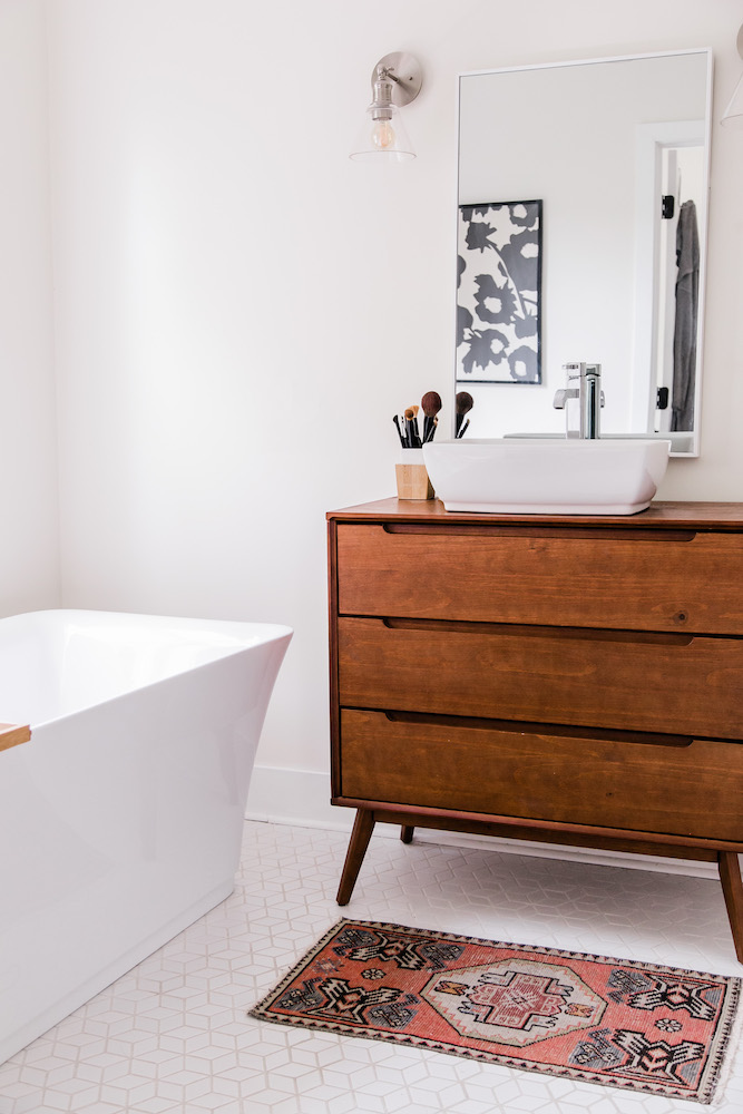 white bathroom with freestanding tub and wood vanity