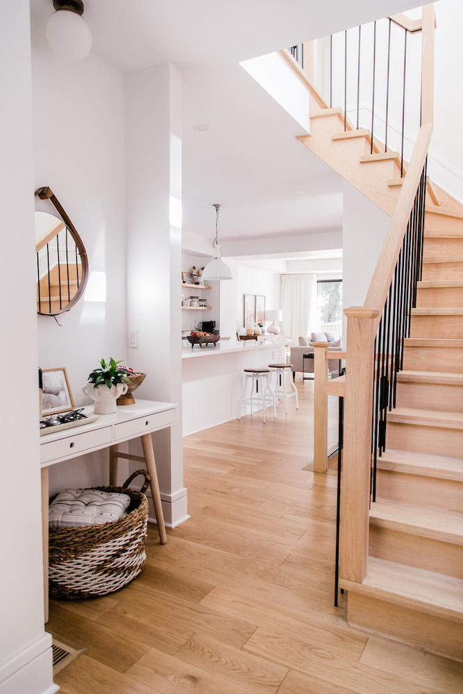 View into bright white kitchen from entryway with stairs