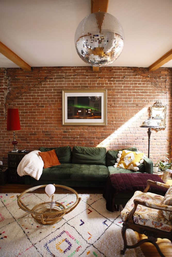 brick-walled living room with green velvet sectional