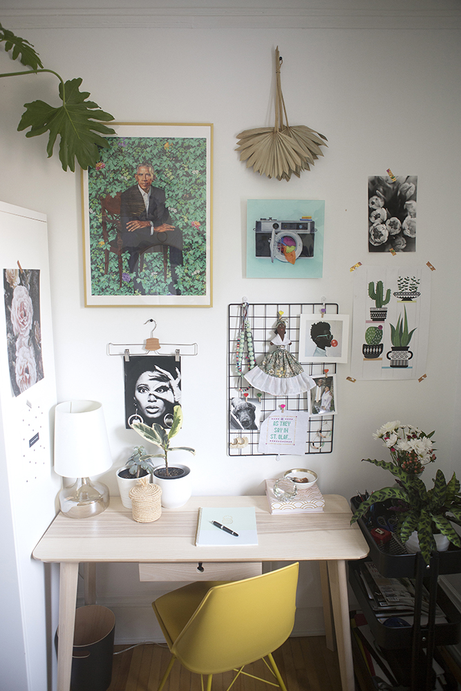 Home office with wood desk, yellow chair and artwork hanging above