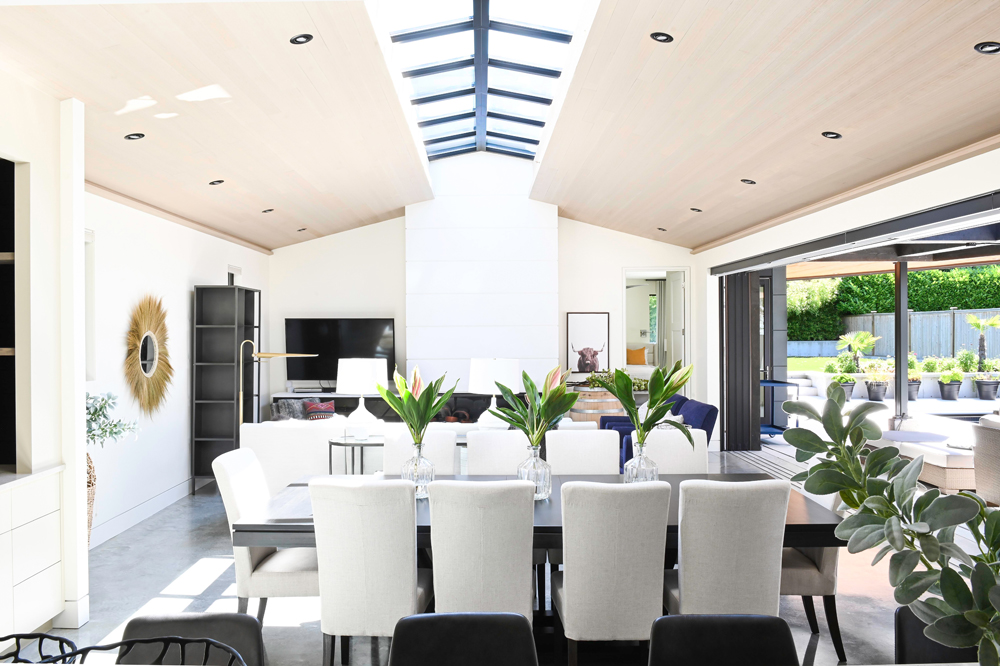 open concept living dining area with centre skylights, dining room table has three leaf arrangement vases