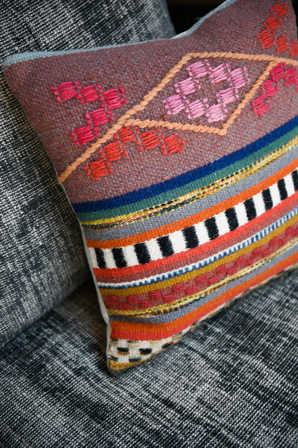 closeup of colourful woven cushion on grey seating