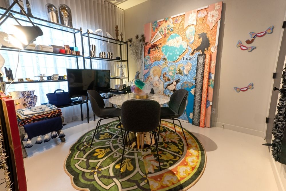 dining room round table, round green and orange rug, bookshelve, artwork that says 'linger'
