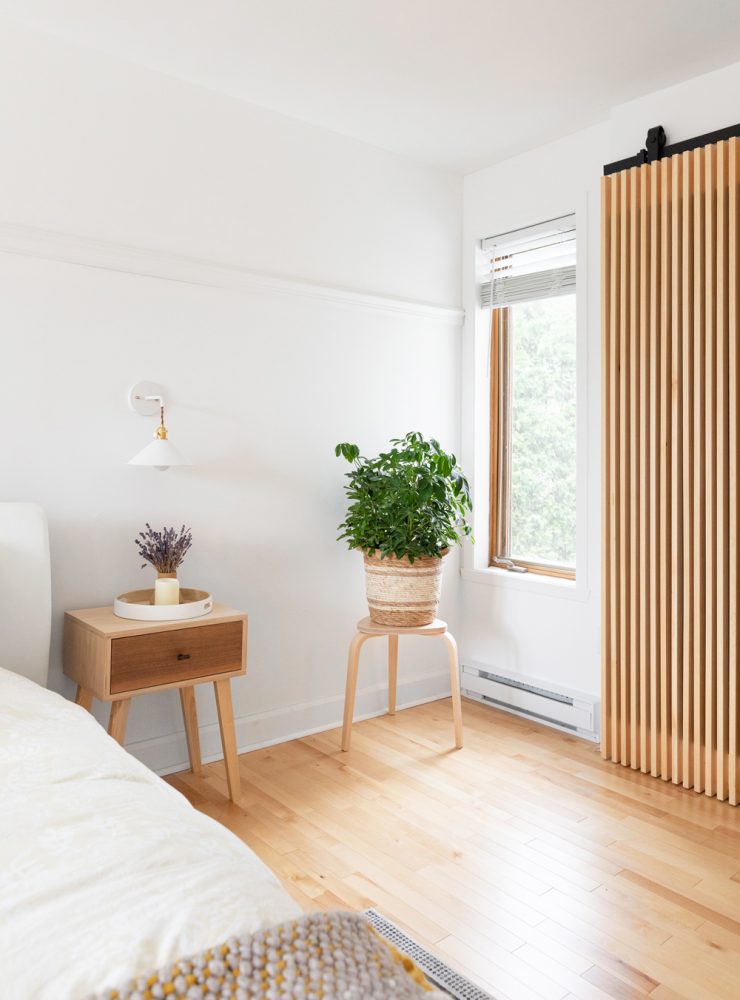 corner of white bedroom with wood-slat sliding door and small window
