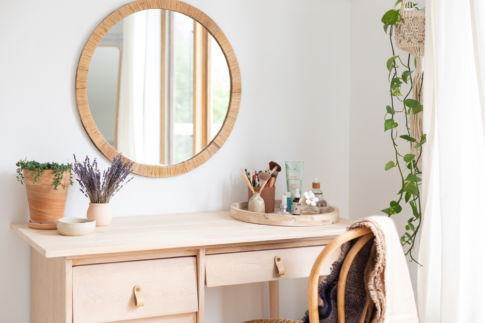 wood vanity with round rattan-framed mirror above it