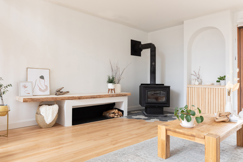 white living room with black fireplace and asymmetrical wood storage area