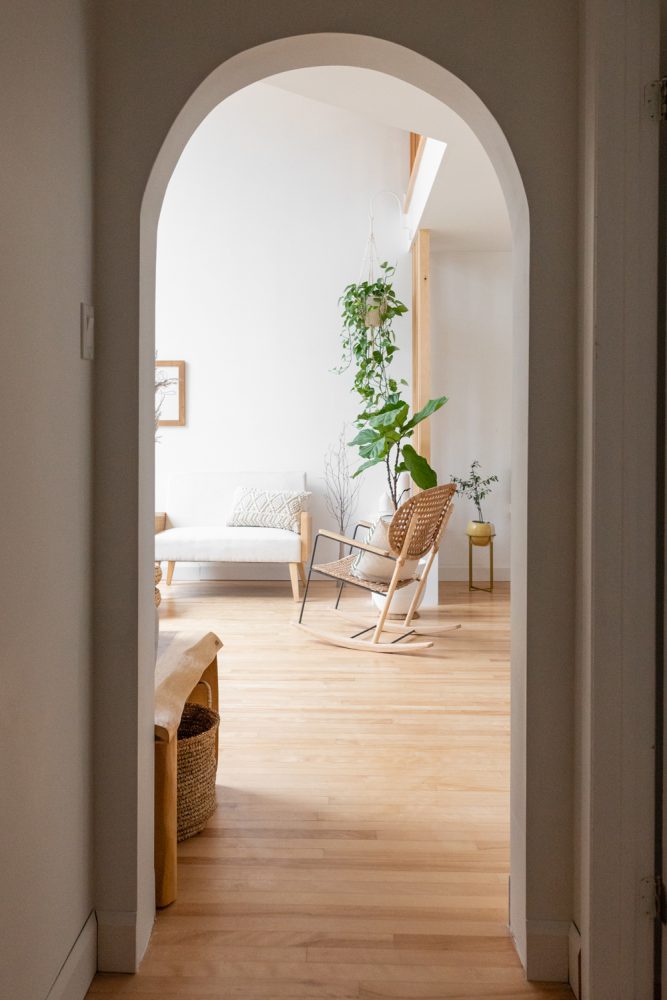 view through arched doorway into light-filled living room with green hanging plant