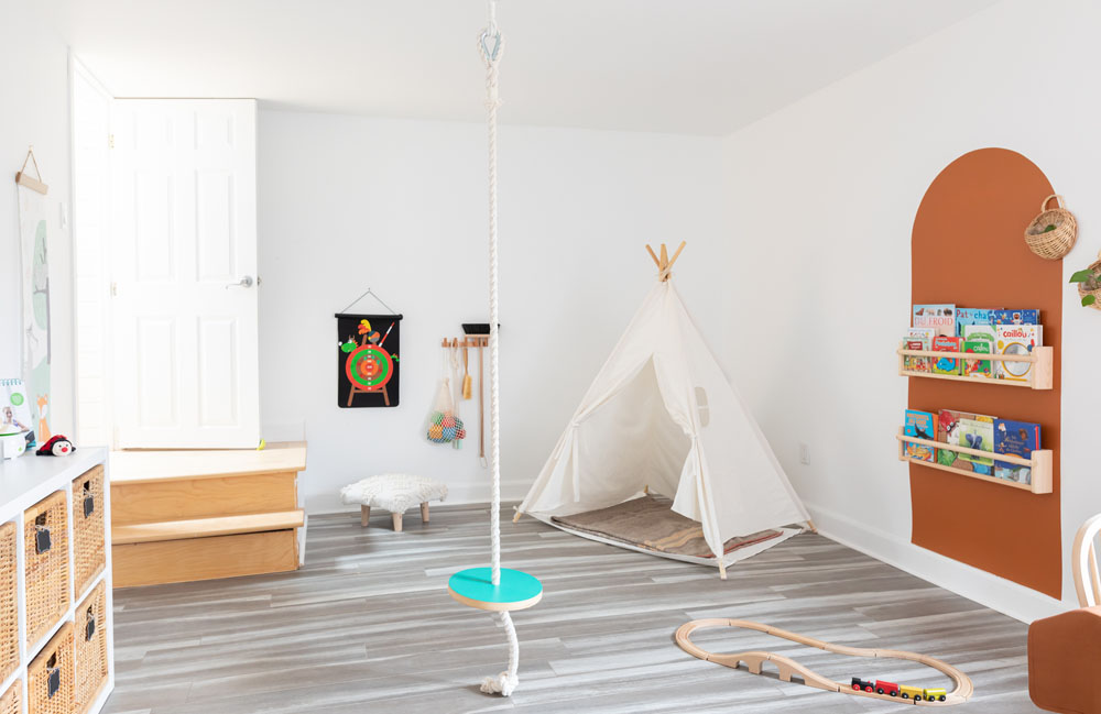 white playroom with colorblocked arch, books and rope swing