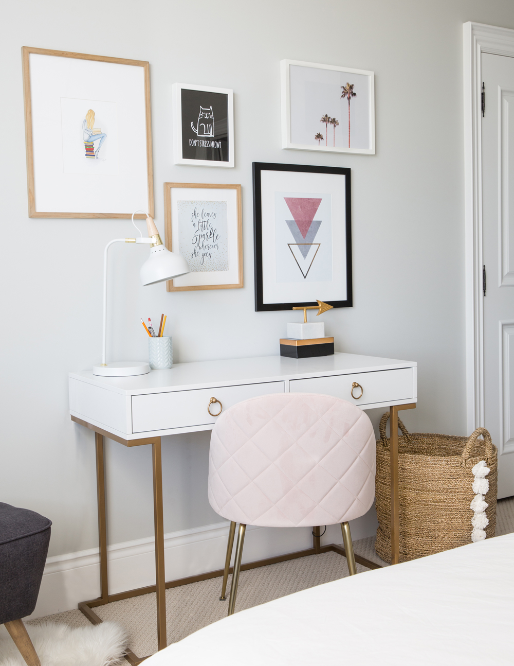 home office with pink quilted chair with brass legs, two drawer desk with round brass pulls, art above desk