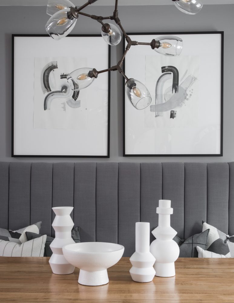 dining room table with grey banquette and two hanging wall art pictures