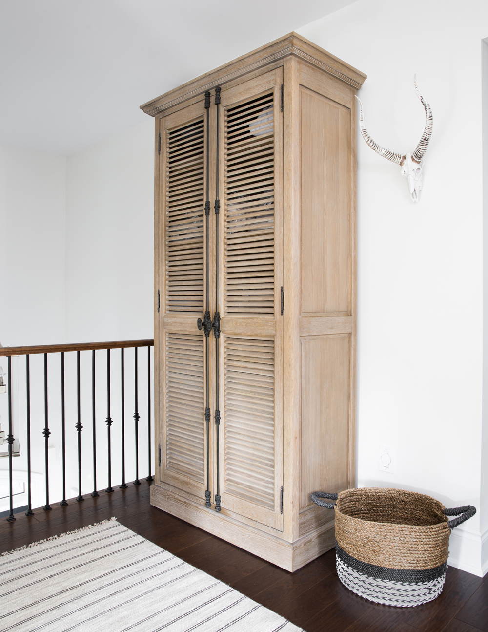 wood cabinet with louvered door, basket on floor