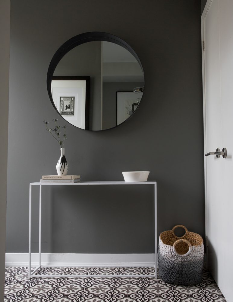 charcoal grey hallway with round mirror and small table