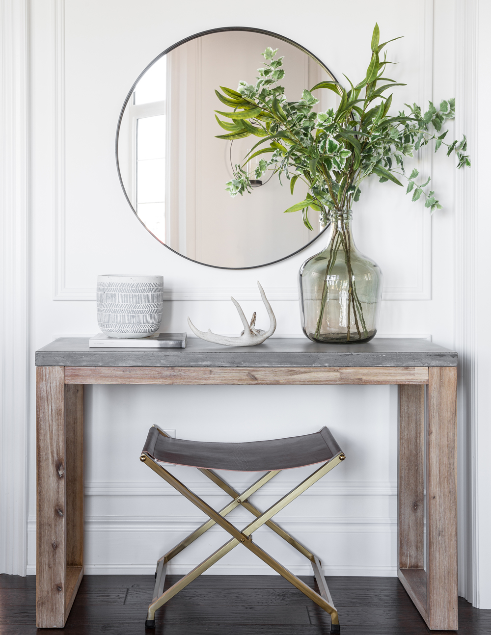 round mirror, console table, brass and leather stool