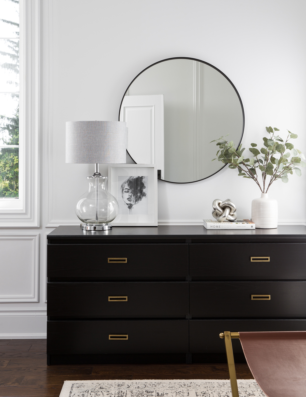 black dresser, round mirror, clear based lamp