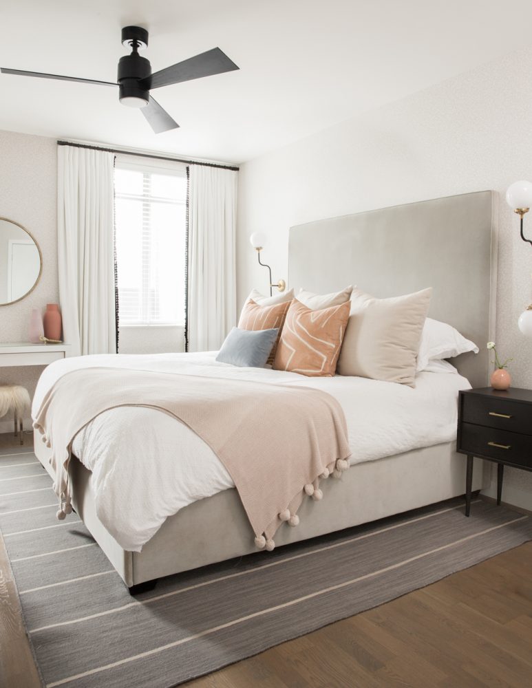 neutral bedroom with a mix of pillows and blankets on white bed