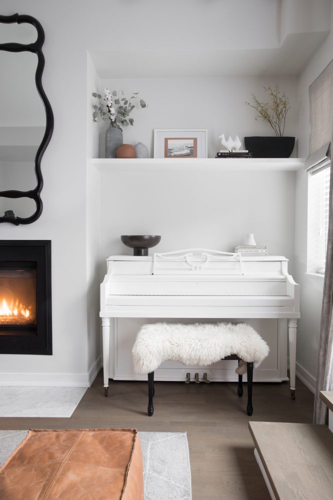 white living room with white piano and fuzzy piano bench
