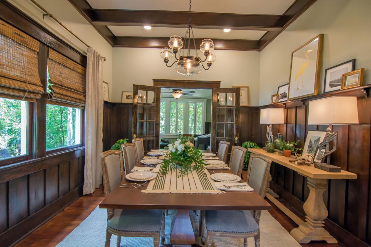 A dining room with paneled walls and exposed wood beams.