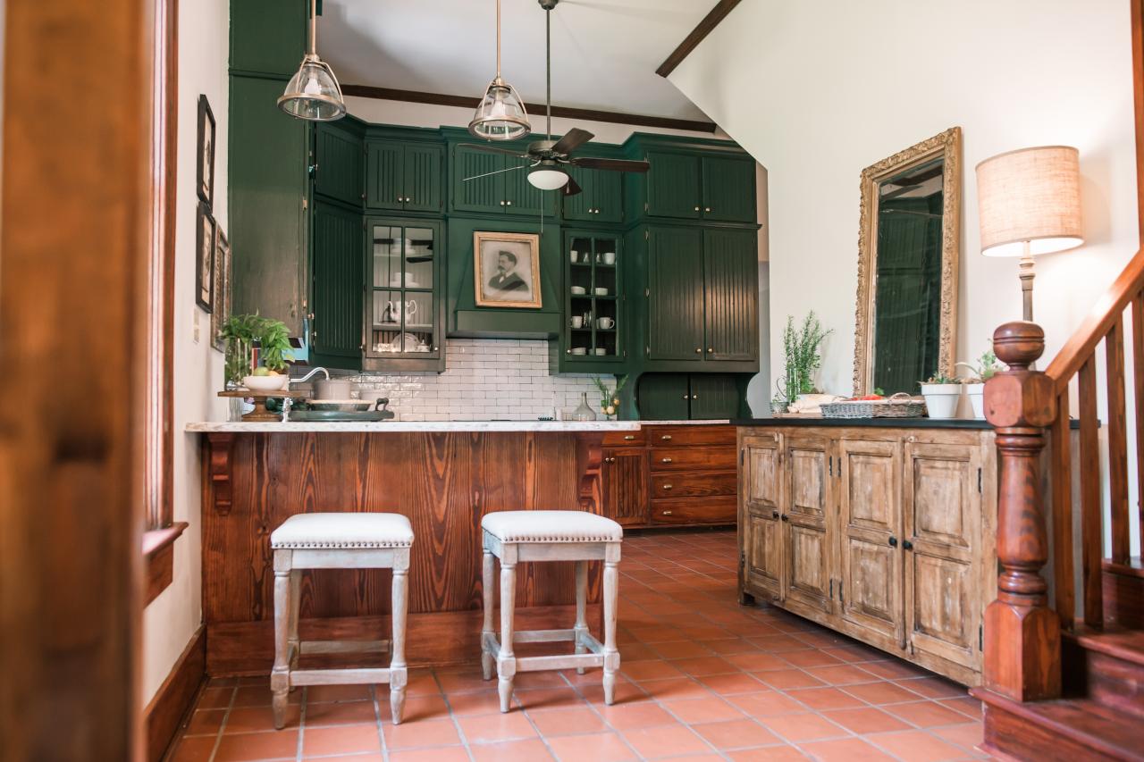 A kitchen with terracotta floors and green cabinets.